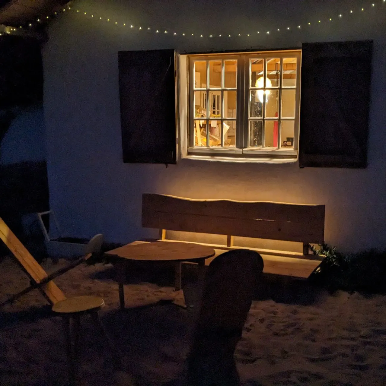 The community house window glowing at night under fairy lights