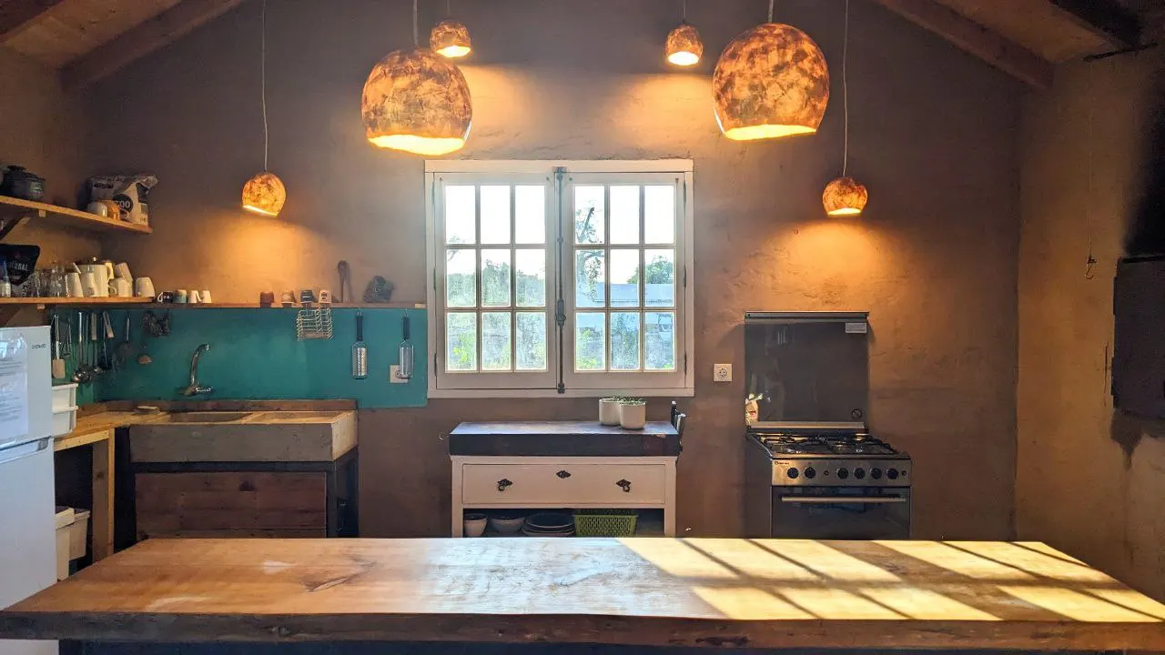 The shared kitchen with a long wooden counter and warm pendant lamps