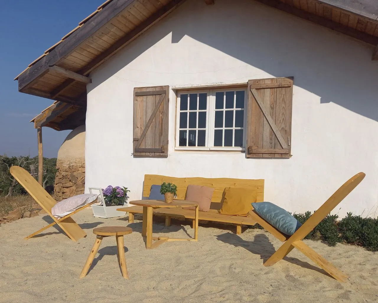 The sandy terrace in front of the community house with wooden lounge chairs