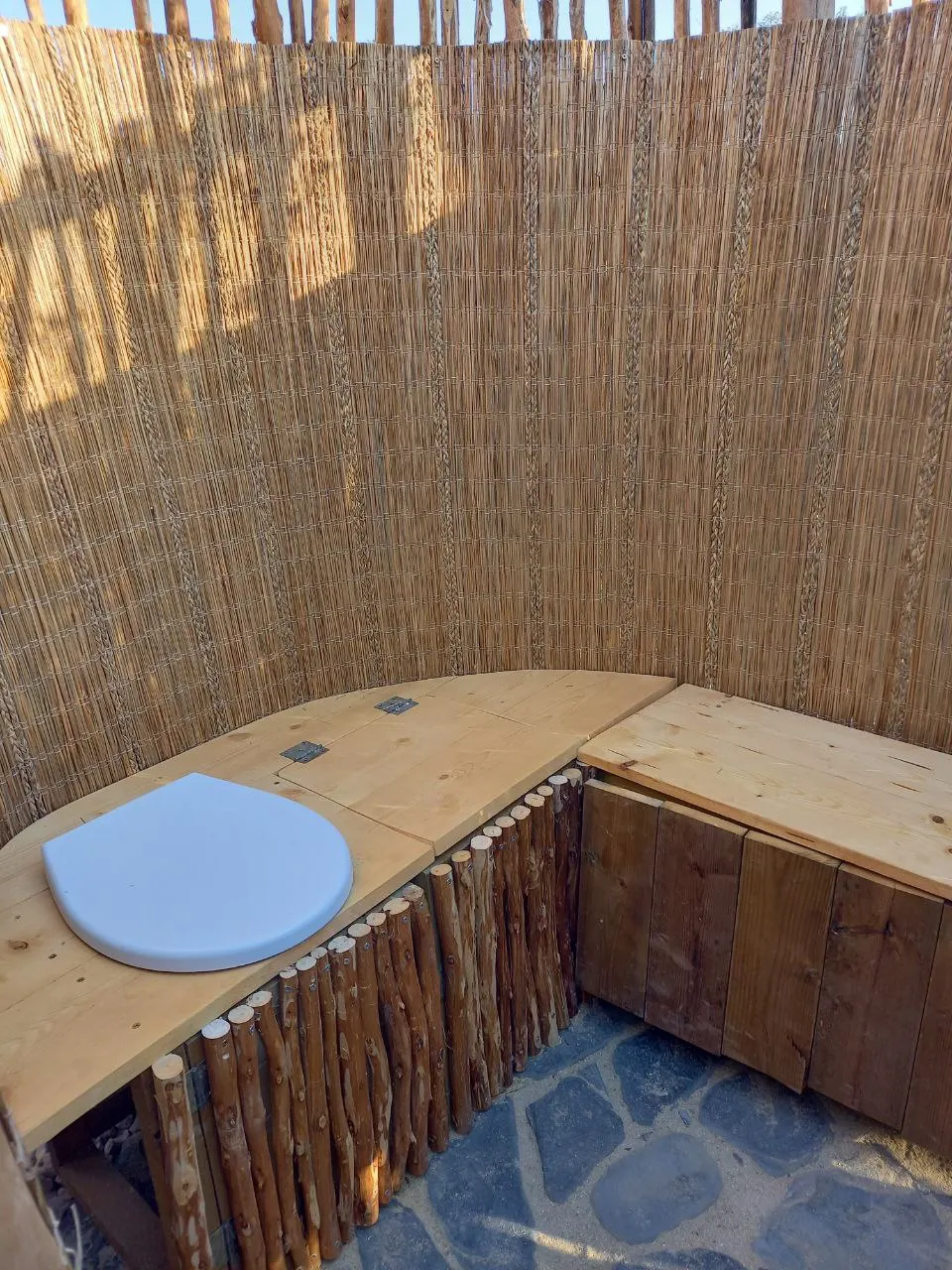 An outdoor dry toilet inside a reed screen