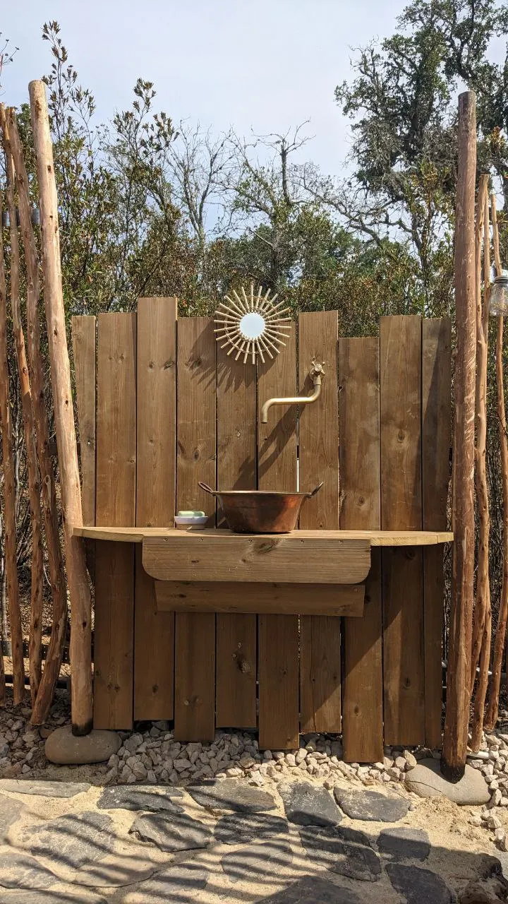 The wooden outdoor washbasin with a sun-shaped mirror