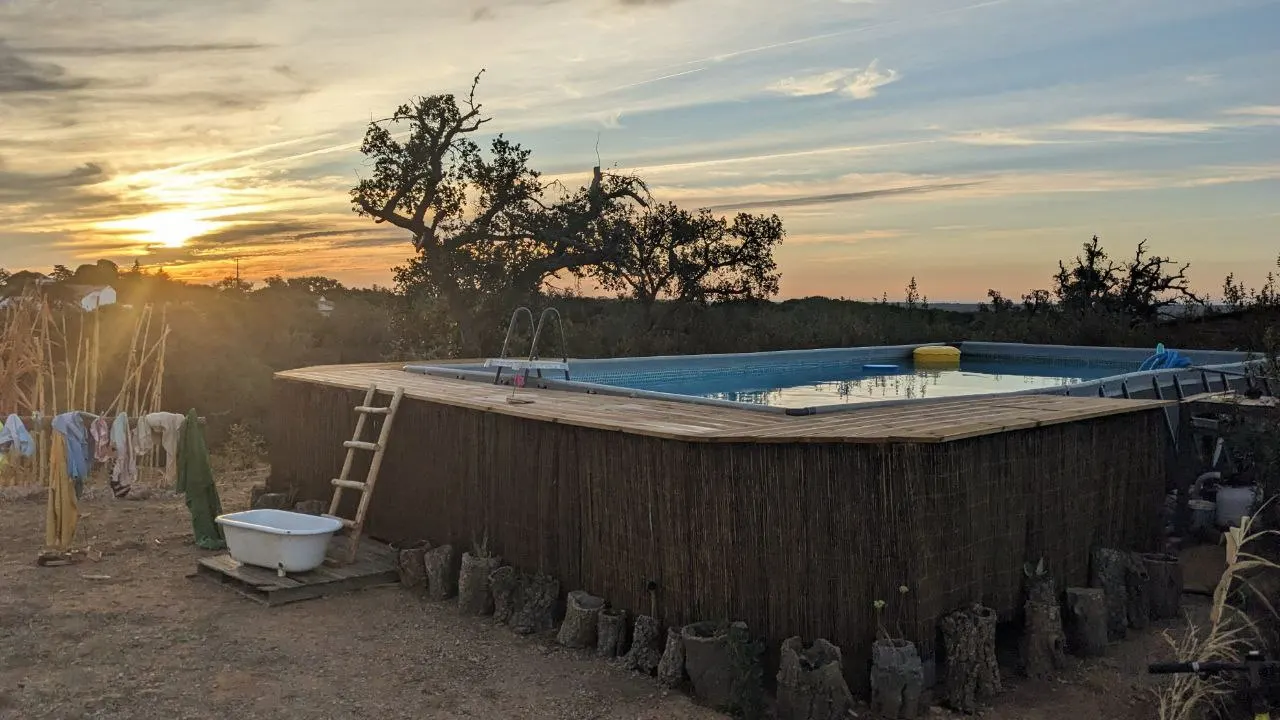The natural swimming pool at sunset with the community house behind