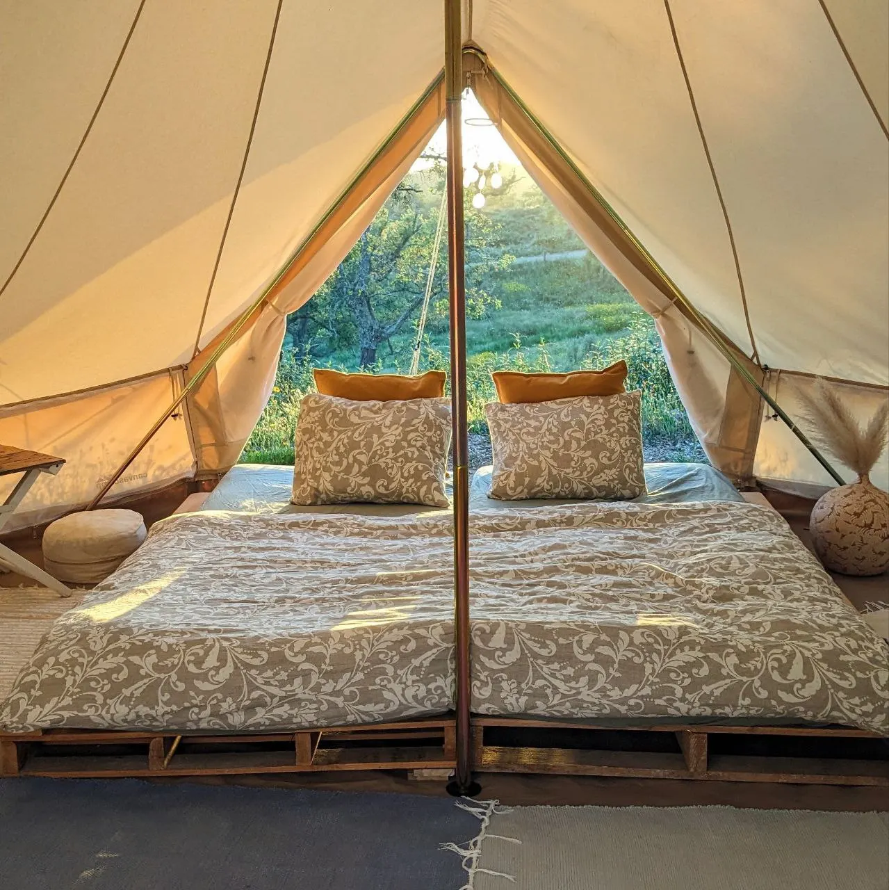 Inside a belltent at Malama, looking out onto green meadows at sunrise