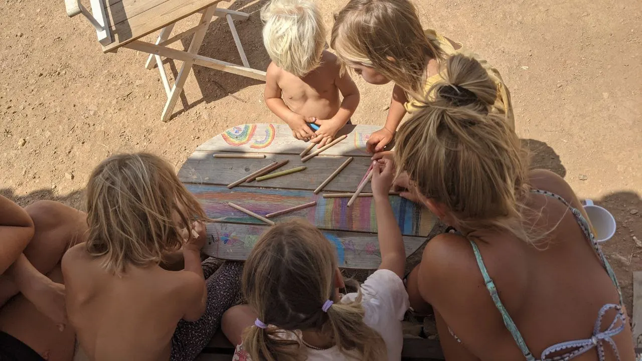 Children drawing together around an outdoor table