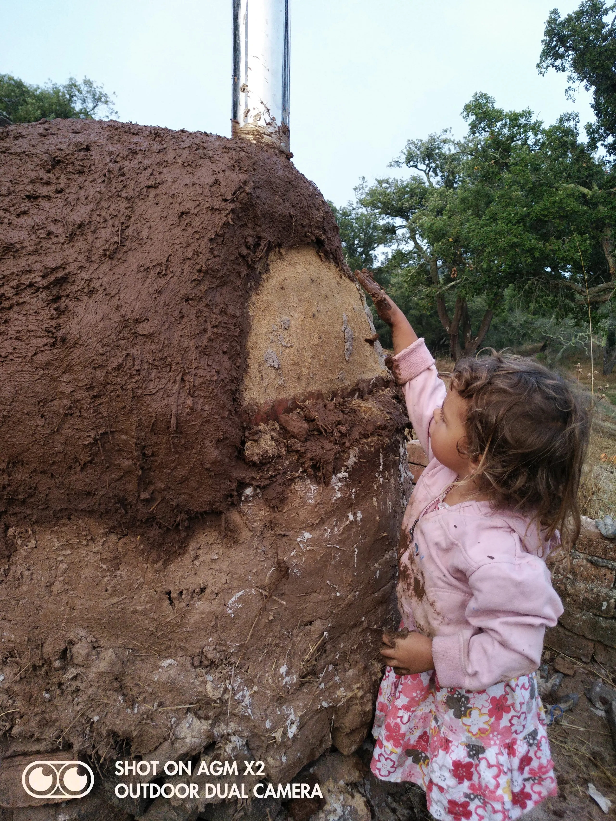 A young child helping to build with earth at Malama