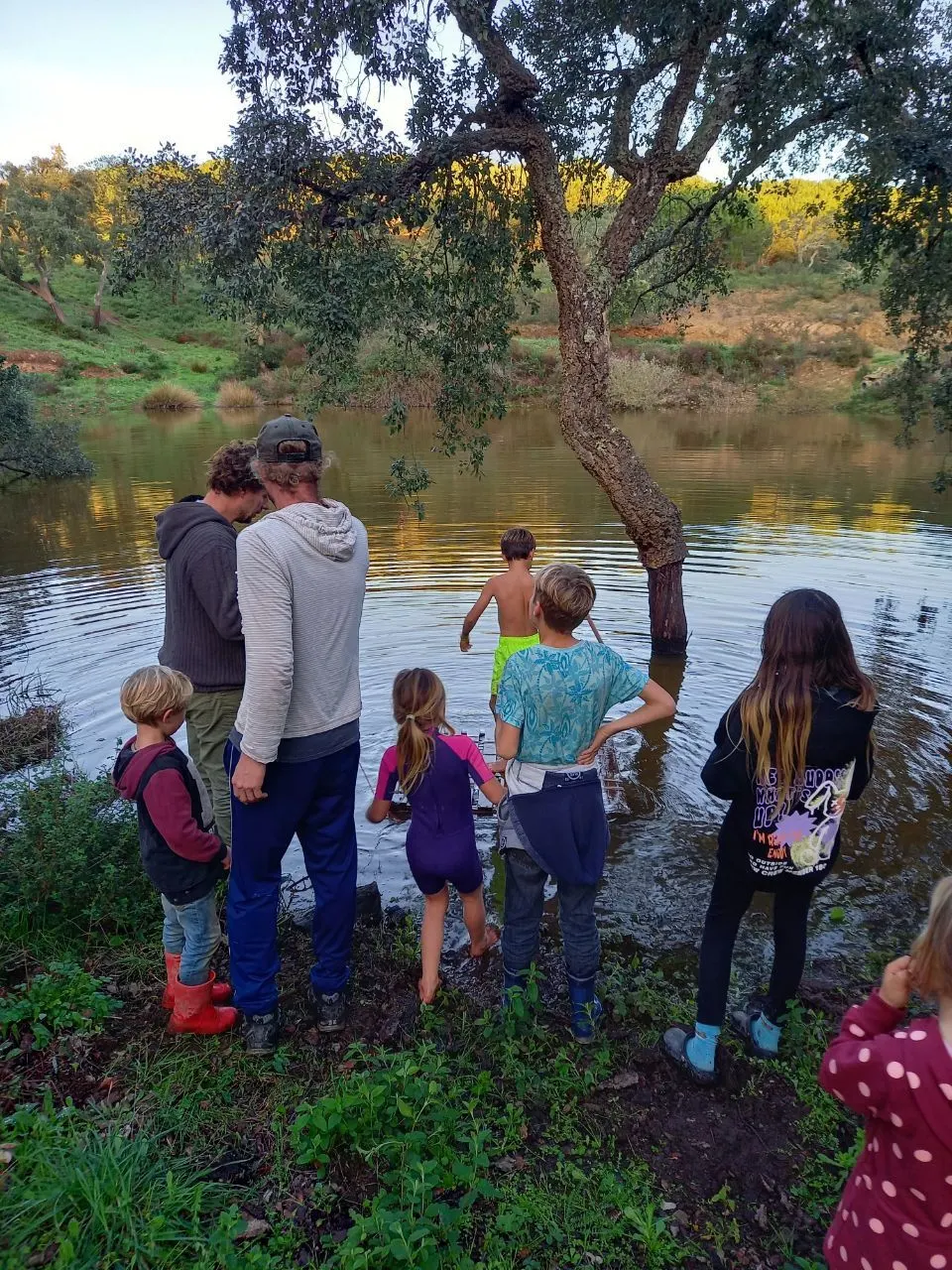 Adults and children gathered beside the pond at Malama
