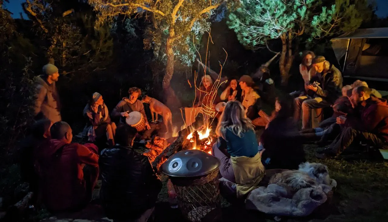 A community gathering with music around an evening fire