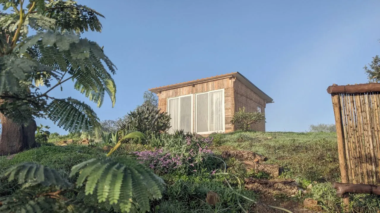 The small wooden Malama Lodge on a green hillside under a blue sky